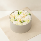 Round box packed with white and ivory soap roses, seen from above on cotton-rag paper