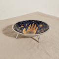 Midnight blue enamelled dish with a golden hamsa hand, standing on three legs