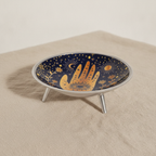 Midnight blue enamelled dish with a golden hamsa hand, standing on three legs