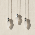 Three clear quartz pendulums with silver caps hanging from fine chains