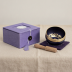 Brass and black singing bowl with striker, purple cushion and lilac box