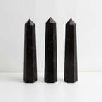 Three black tourmaline obelisks side by side, showing the variation from piece to piece