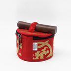 Red brocade carry case for the mini singing bowl with the wooden striker strapped on top