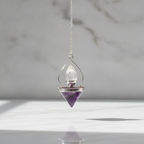 Amethyst and quartz pendulum on its chain, marble background