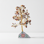 Gemstone tree with painted stone base against a white wall