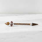 Tiger eye shiva lingam crystal wand lying on a white surface